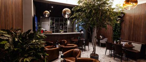 A modern lounge area with leather seating, a bar, and a large tree.