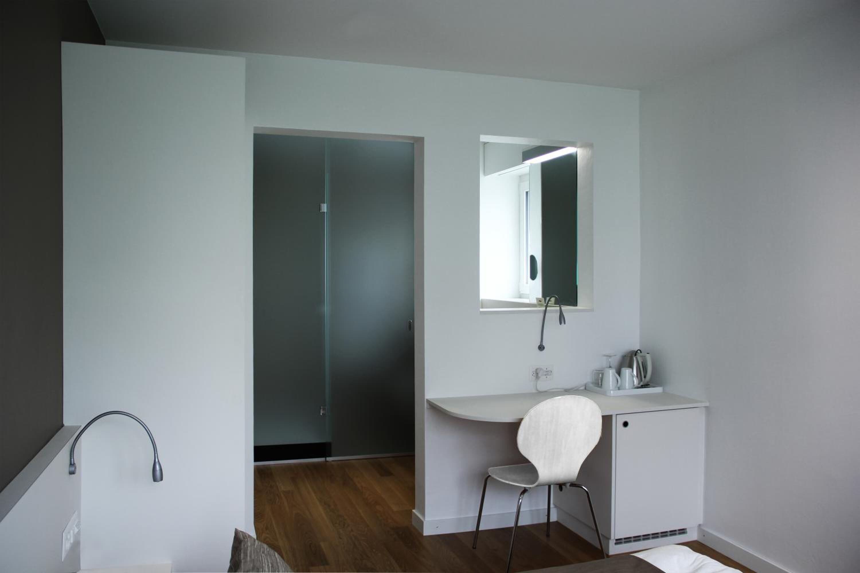 A modern bathroom with a white vanity, a mirror, and a shower area.