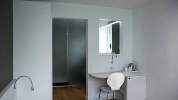 A modern bathroom with a white vanity, a mirror, and a shower area.