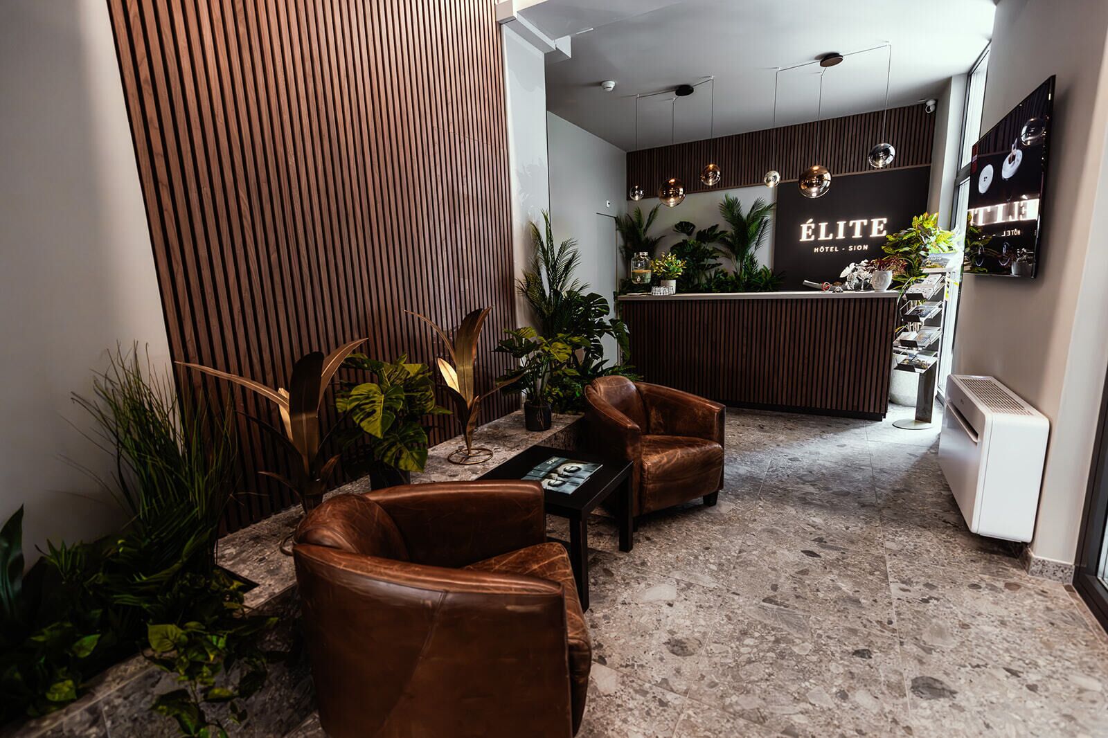 Un hall d’hôtel doté de fauteuils en cuir, d’un comptoir de réception et d’un décor intérieur moderne.