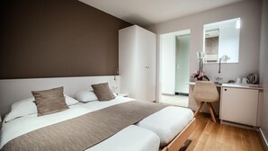 A modern hotel room with a large bed, a desk, and a mirror.