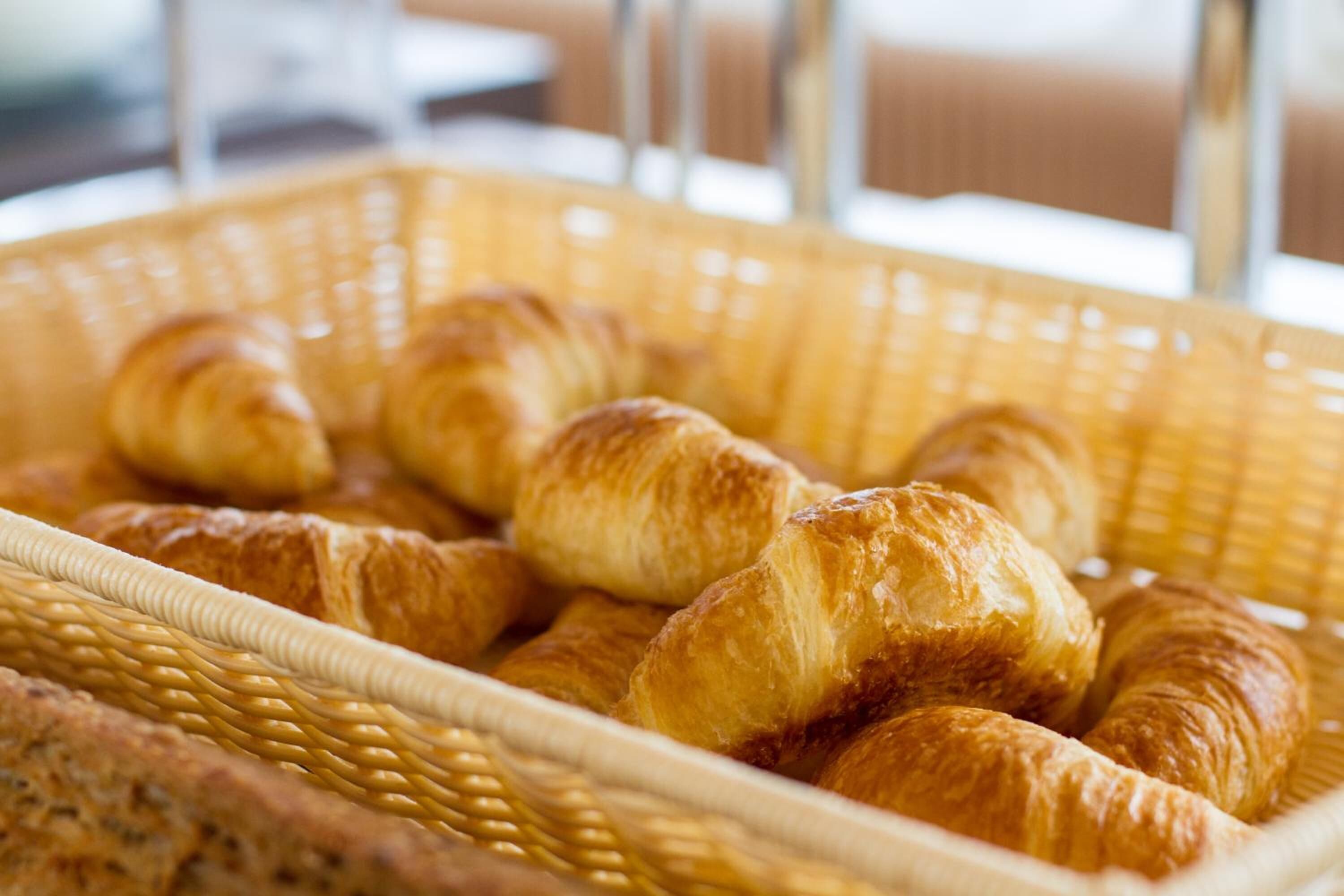 Una cesta con cruasanes y una hogaza de pan.