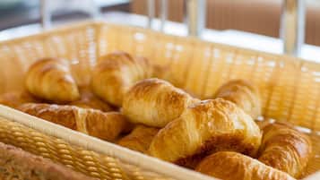 Una cesta con cruasanes y una hogaza de pan.