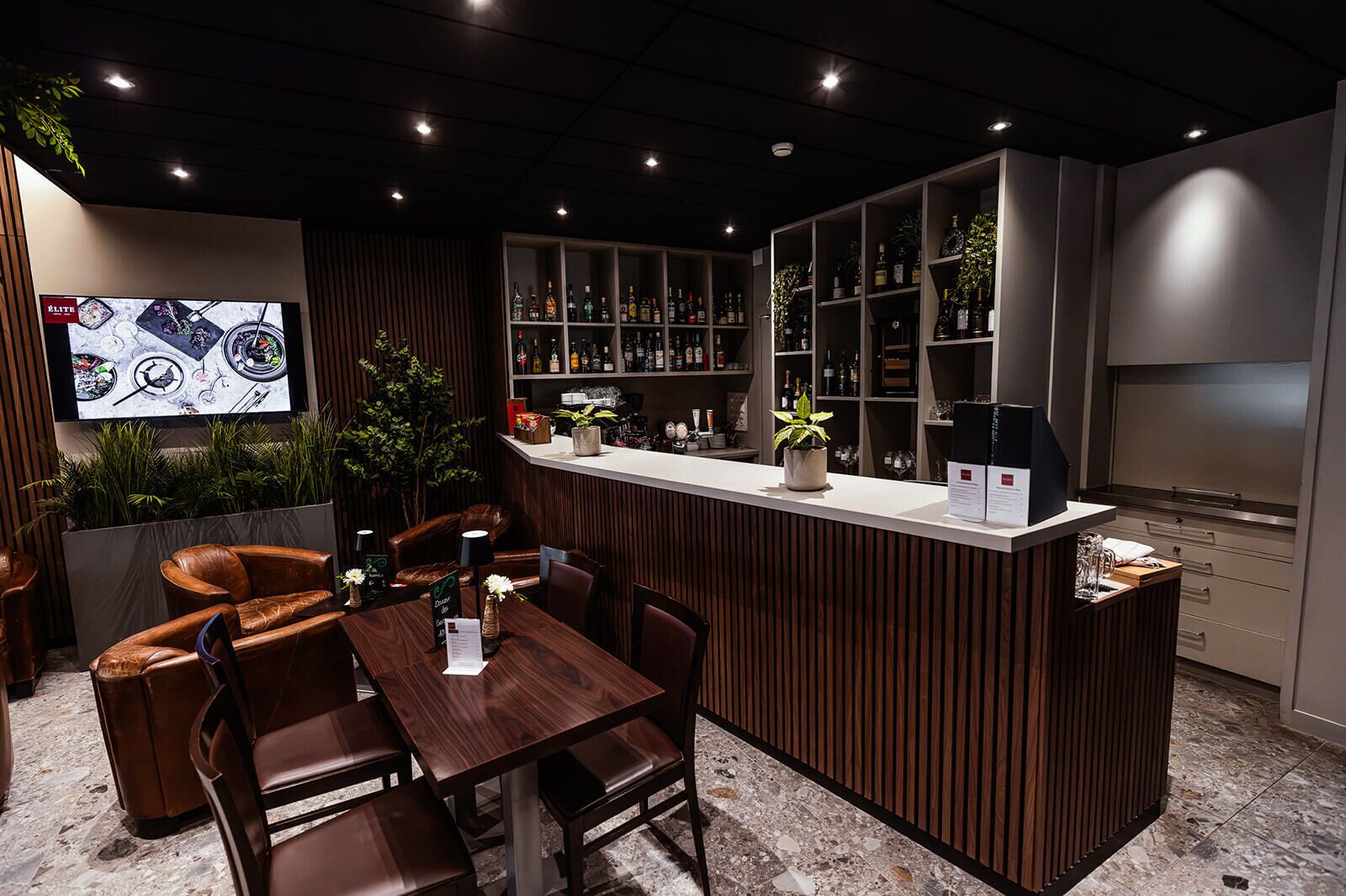 Una zona de bar con mostrador de madera, asientos y una pantalla de televisión.