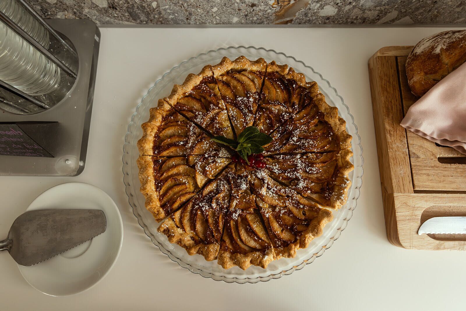 A pie on a glass plate on a kitchen counter.
