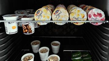 A refrigerator stocked with various food items including yogurt, granola, and jars of preserved fruit.