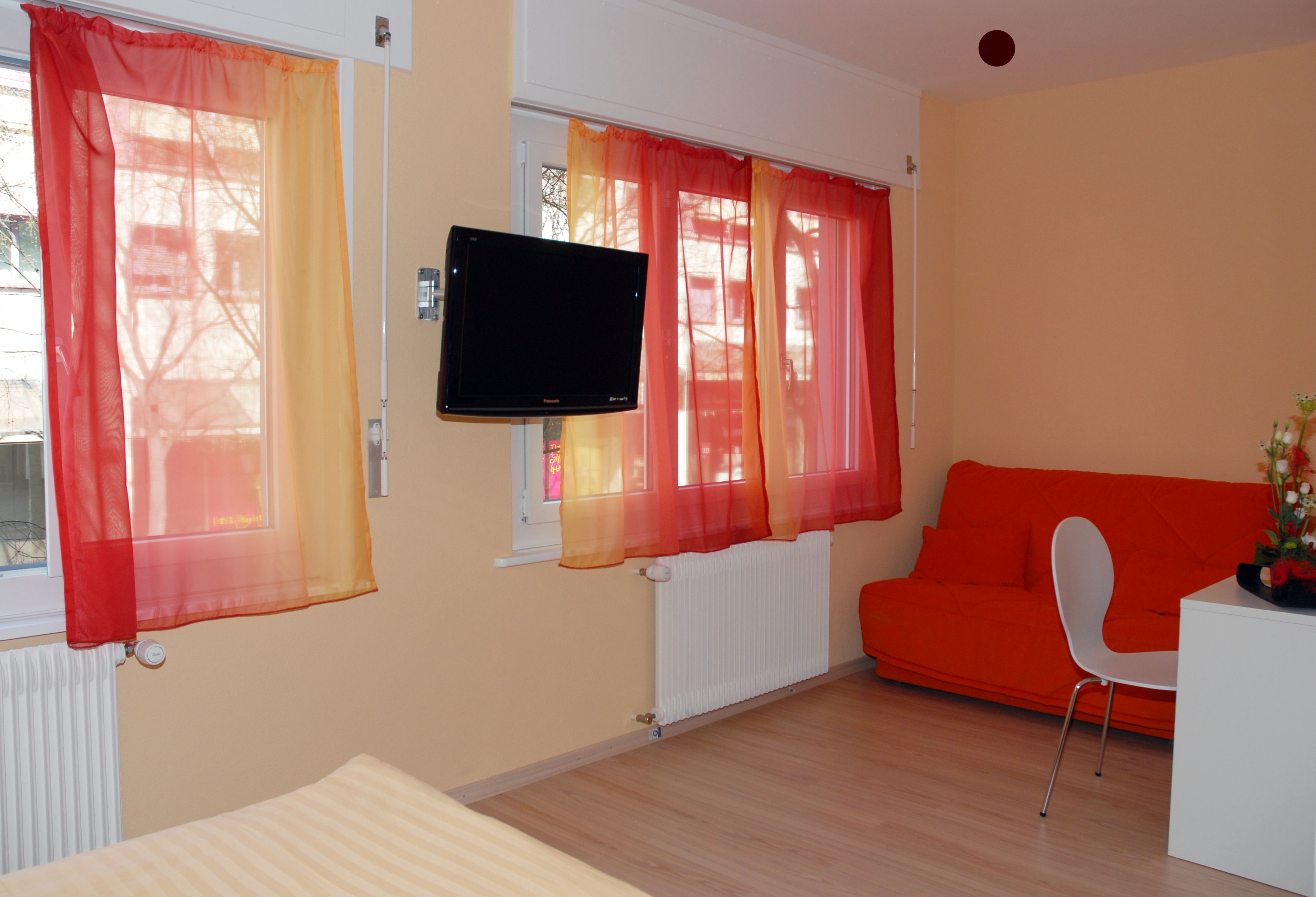 A room with a sofa, a TV, and a chair.