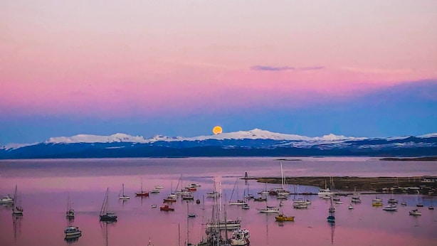 A calm body of water with boats and a mountain range in the background.