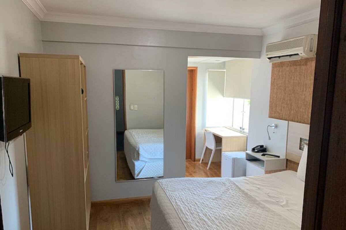 Een hotelkamer met een bed, een bureau, een stoel, een televisie en een kledingkast.