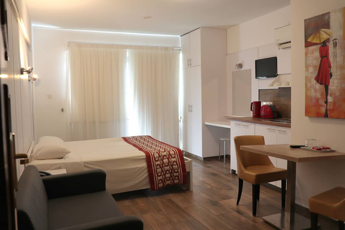 A hotel room with a bed, a desk, a chair, a TV, and a painting on the wall.