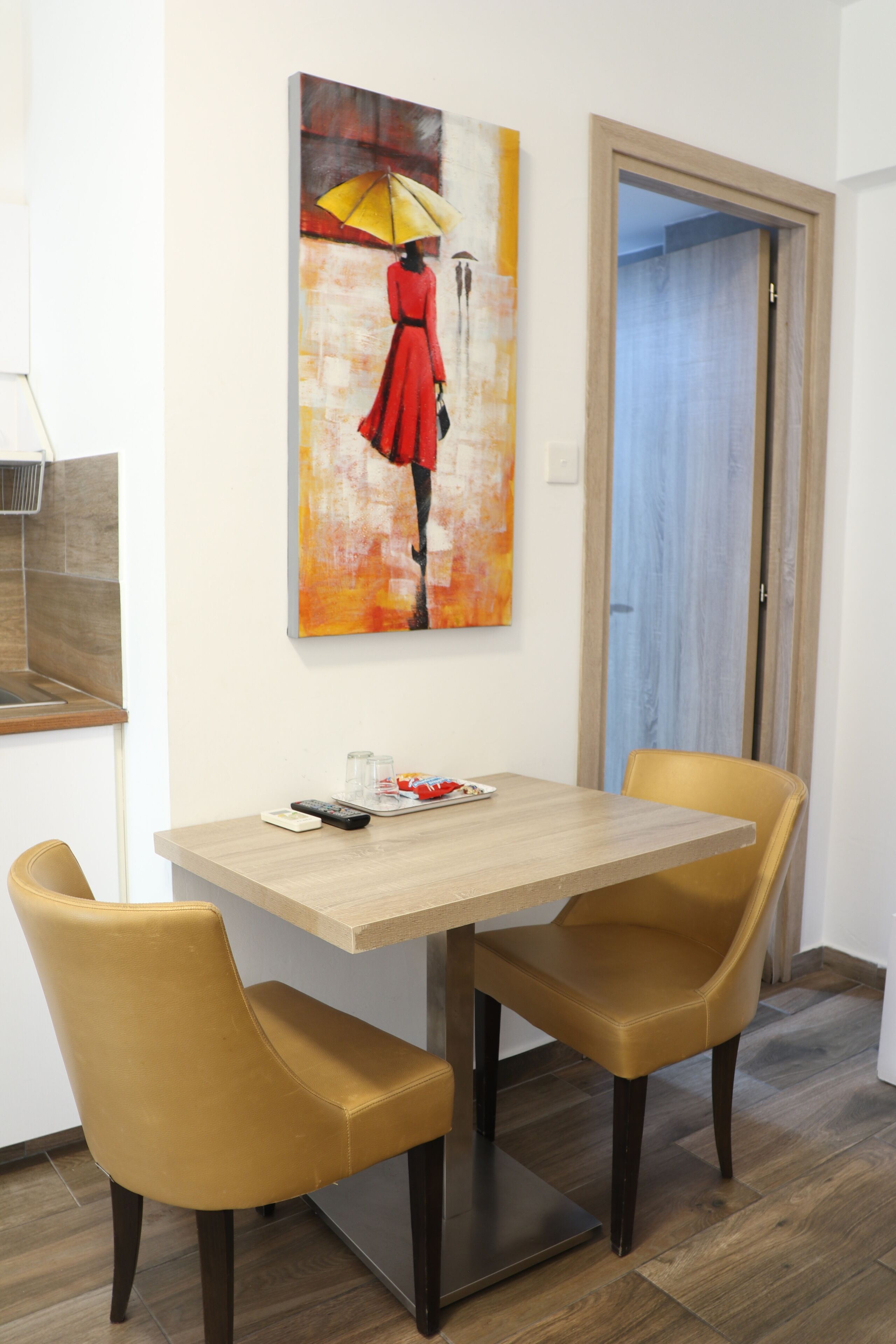 Ein Essbereich mit Tisch und zwei Stühlen, einem Bild an der Wand und einer Tür im Hintergrund.