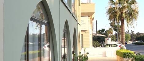 A building with large arched windows and a flat roof. There are potted plants on the sidewalk in front.