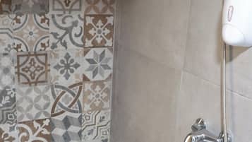 A bathroom with patterned tiles on the walls, a shower with a handheld showerhead, and a white bathtub.