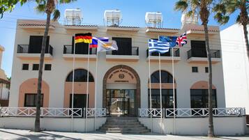 A hotel with a white facade, arched windows, and a central entrance with steps.