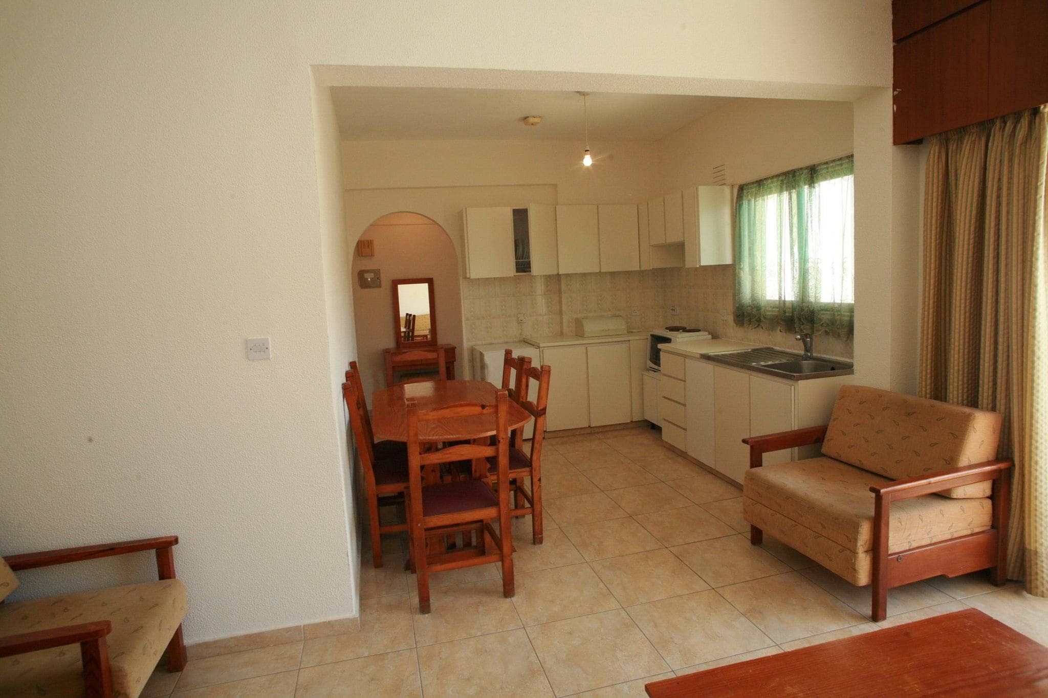 A compact living space with a dining area, kitchenette, and a sofa.