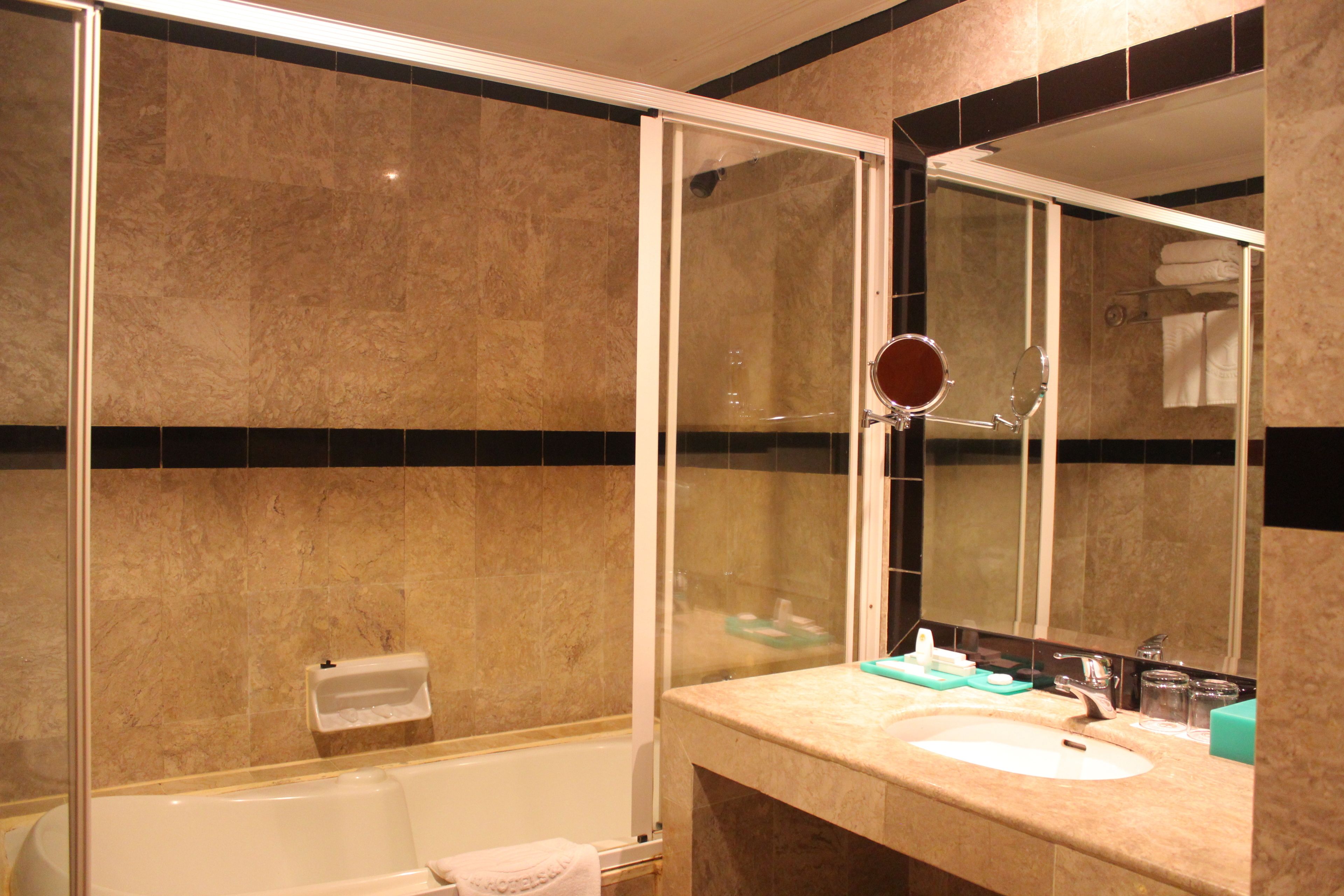 A bathroom with a bathtub, a sink, a mirror, and a towel rack.