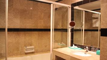 Un baño con bañera, lavabo, espejo y toallero.