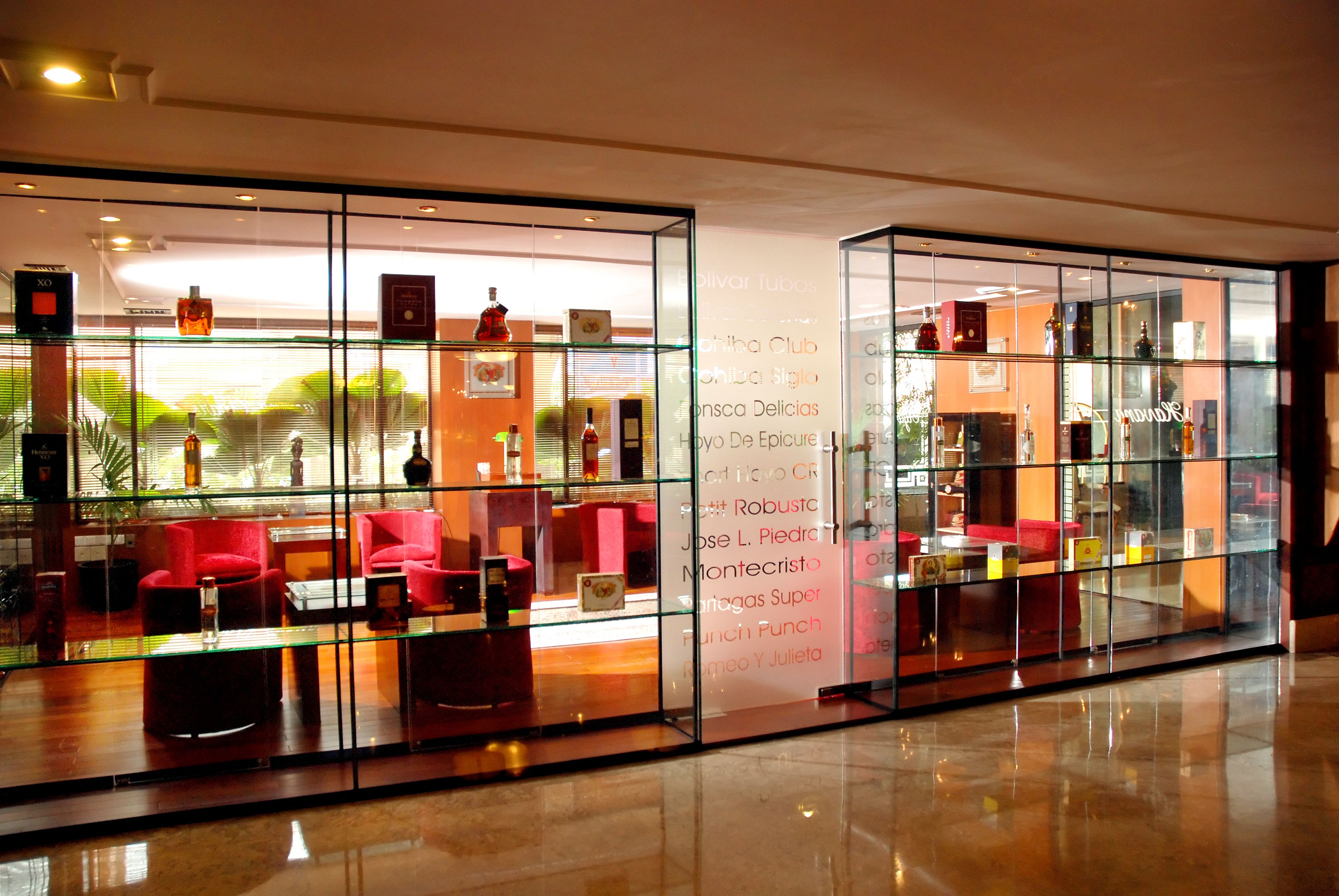 Un moderno vestíbulo de hotel con divisiones de vidrio, asientos rojos y suelo pulido.