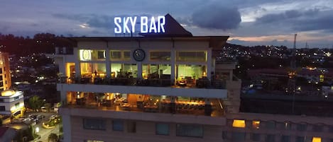 Un hotel con un llamativo letrero que dice "SKY BAR" en la azotea.