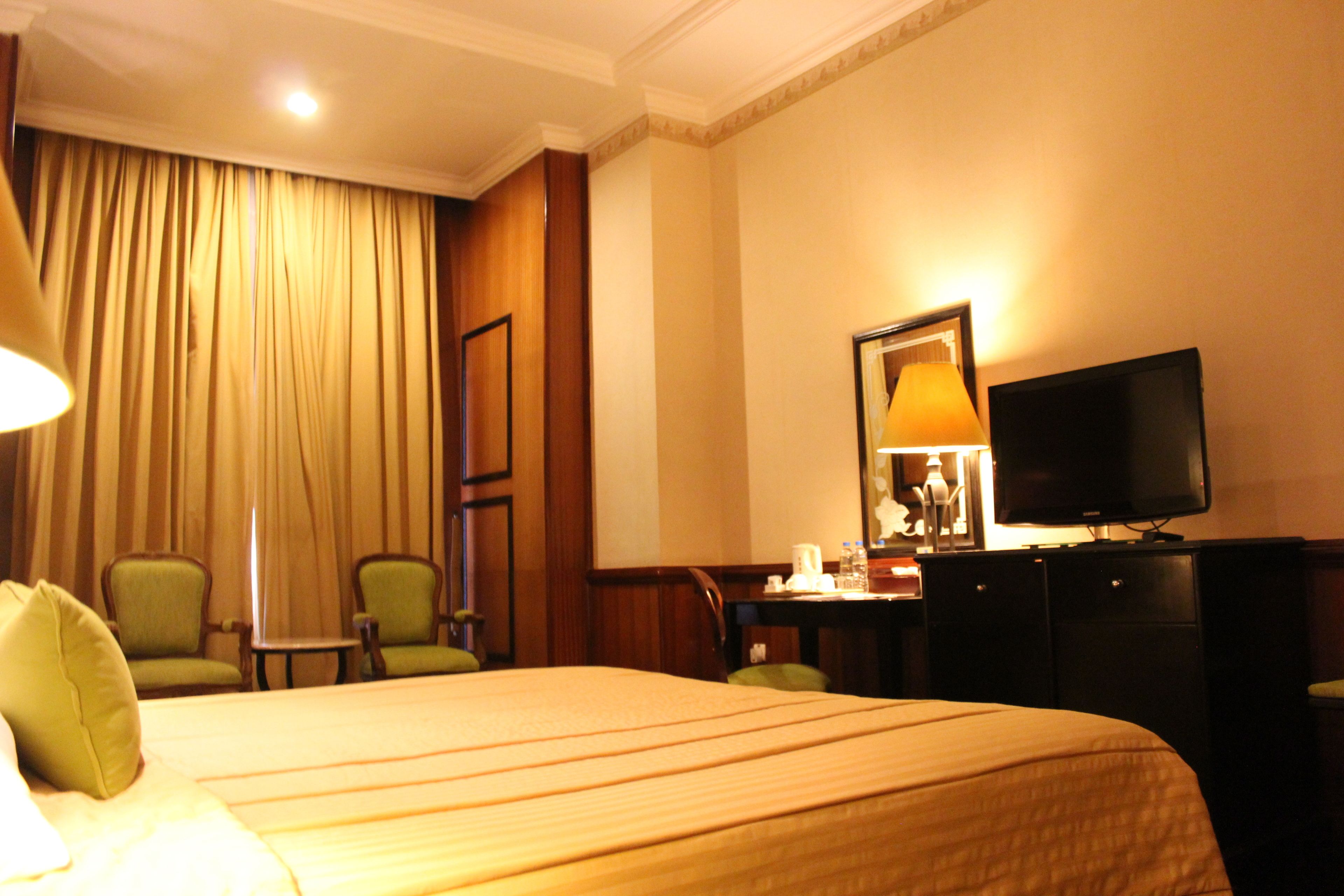 A hotel room with a bed, a television, a desk, and two chairs.