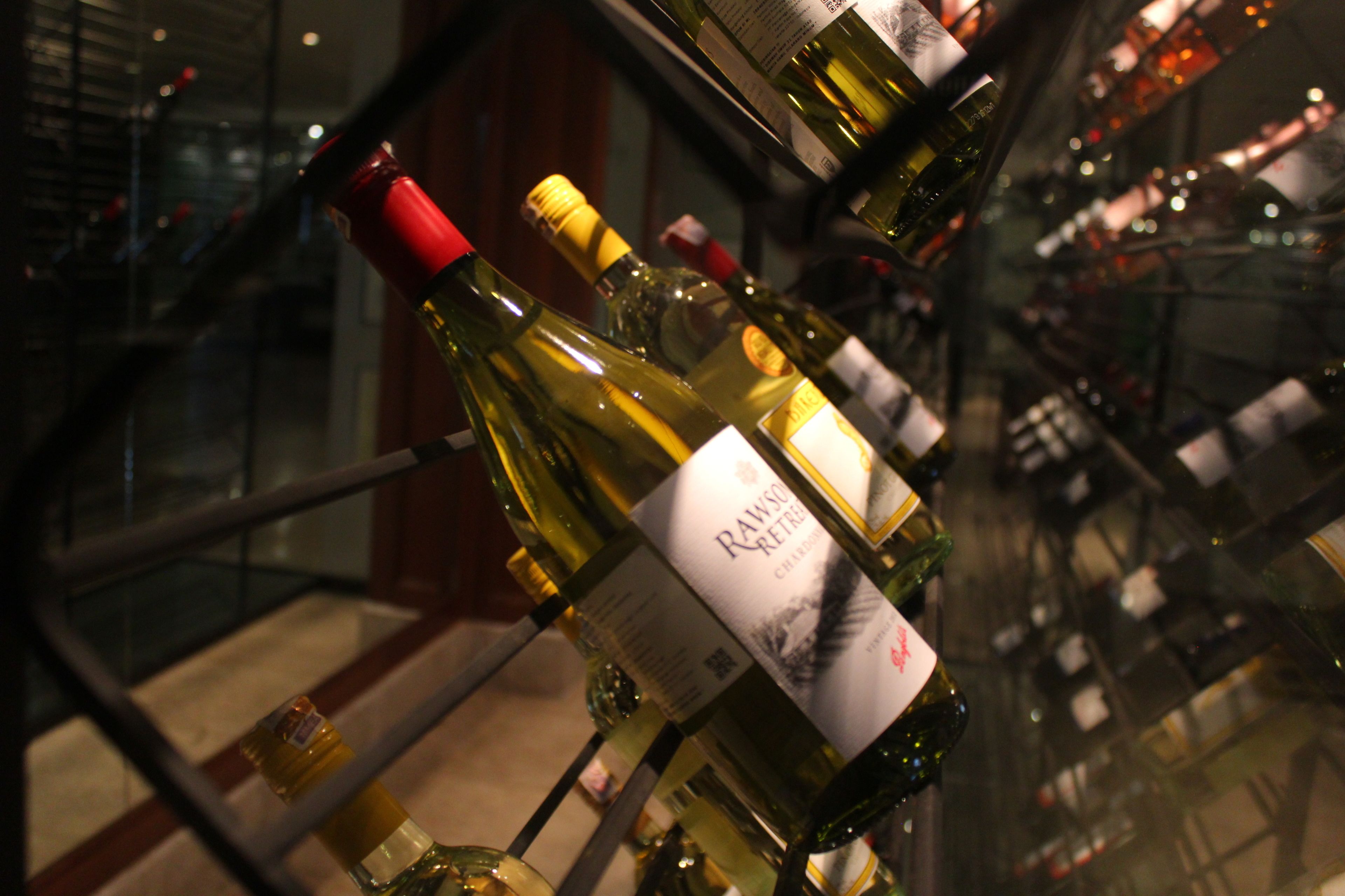 A collection of wine bottles displayed on a glass shelf.