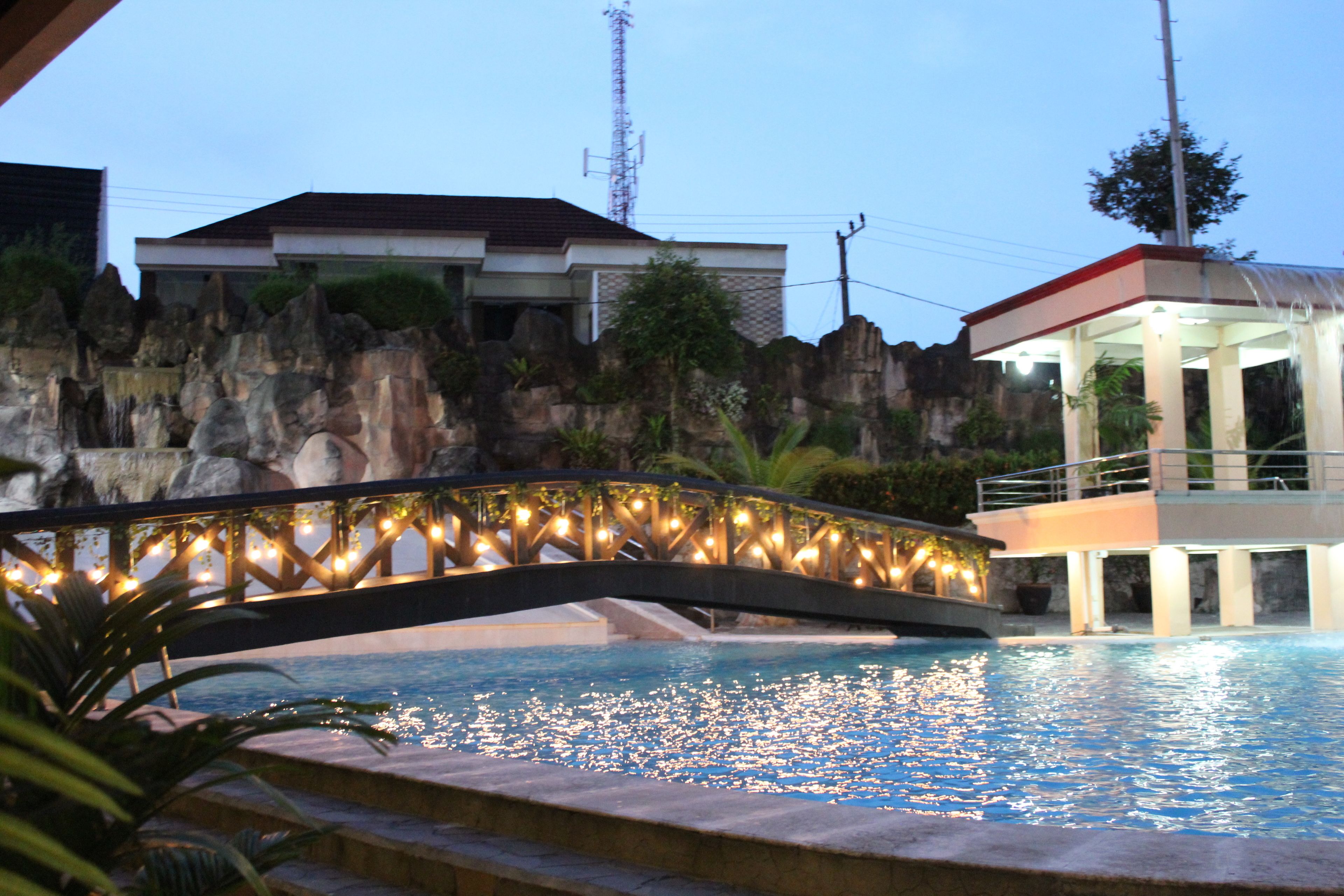Una piscina con un puente de piedra, una torre de salvavidas y un edificio al fondo.