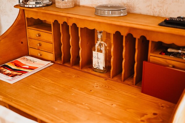 Un cofre de madera con una botella de licor y una revista sobre una mesa de madera.