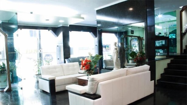 Um lobby moderno com um sofá branco, uma mesa de centro e plantas em vasos.