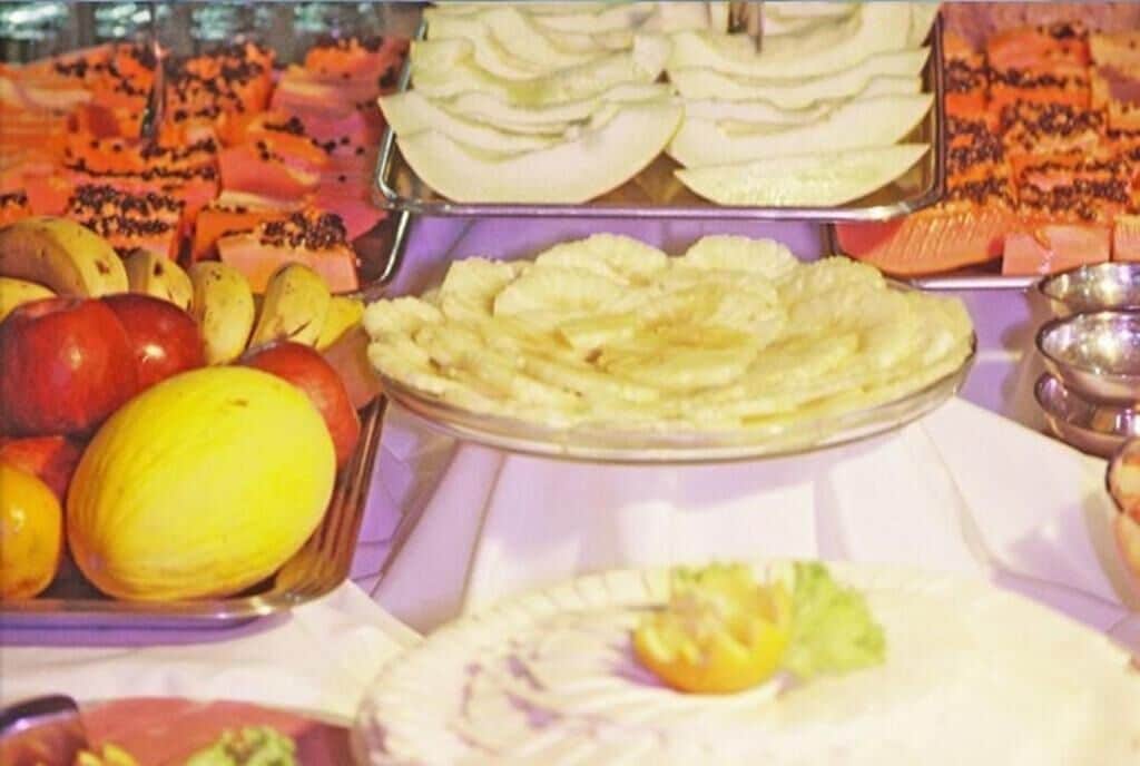 Un buffet proposant une variété de fruits et de légumes, notamment des pommes, des oranges et un melon.