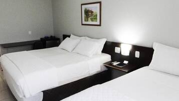 A hotel room with two beds, a nightstand, and a framed picture on the wall.