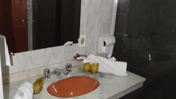 A bathroom with a marble sink, a mirror, a towel, and a shower area.