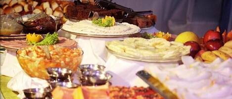 A buffet table with various dishes including salads, meats, and desserts.