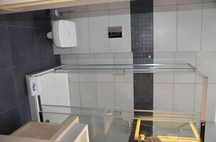 A modern bathroom with a glass shower enclosure, a white toilet, and a towel rack.