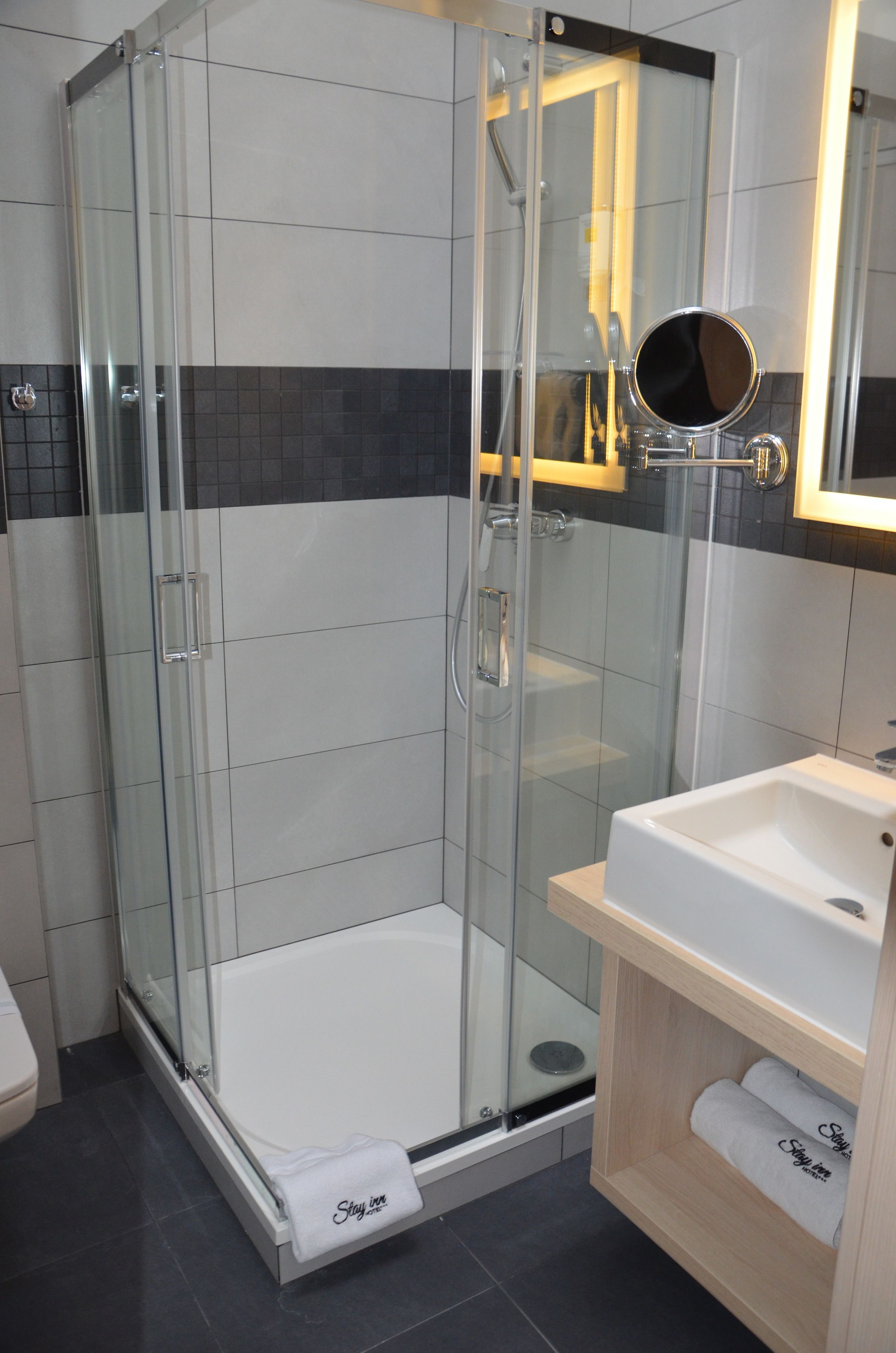 Ein modernes Badezimmer mit einer gläsernen Dusche, einem weißen Waschbecken und einem Spiegel darüber.