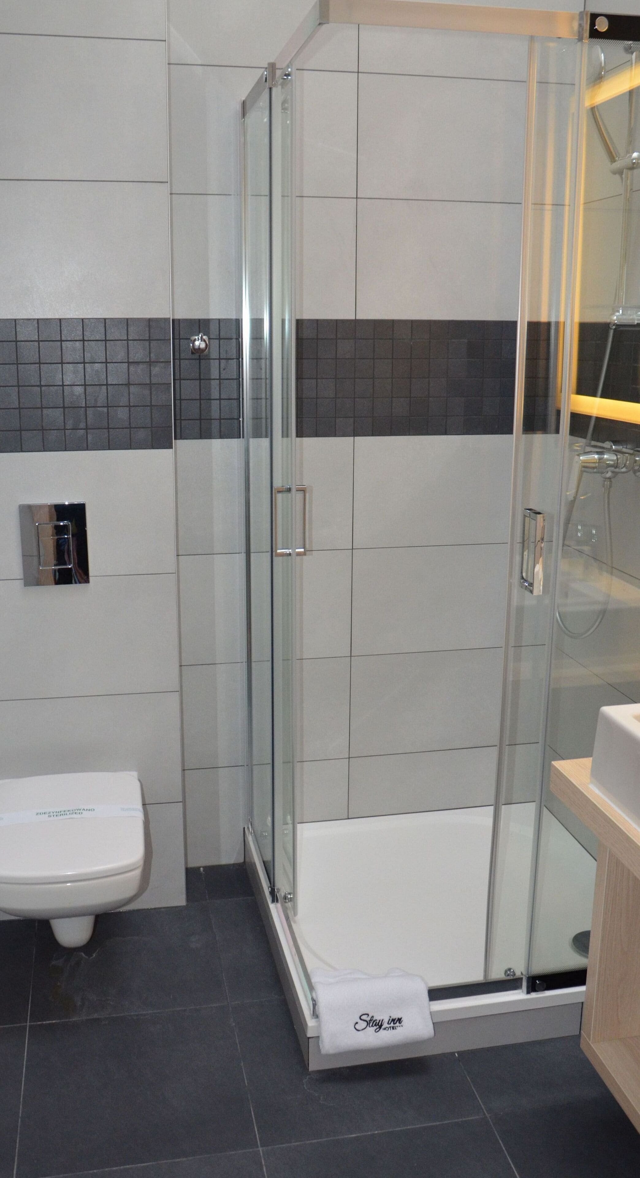 A modern bathroom with a glass-enclosed shower, a white toilet, and a towel rack.