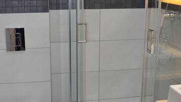 A modern bathroom with a glass-enclosed shower, a white toilet, and a towel rack.