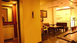 Un vestíbulo de hotel con mostrador de recepción, zona de estar y un cuadro en la pared.