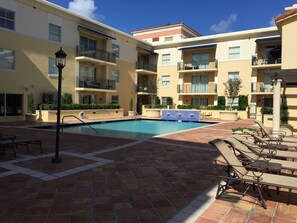 A pool area with lounge chairs and a tiled deck. - LYX Suites at Merrick Park in Coral Gables (Coral Gables)