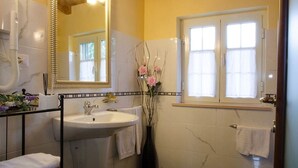 A bathroom with a white sink, a mirror, and a window with white curtains. - Bed and Breakfast Charme (Sora)