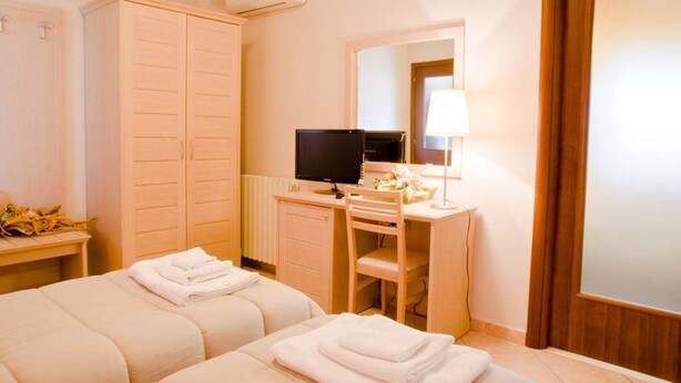 A hotel room with two beds, a desk with a computer, a mirror, and a radiator. - Bed and Breakfast Charme (Sora)