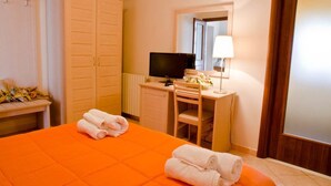 A hotel room with a bed, a desk with a computer, a lamp, and a mirror. - Bed and Breakfast Charme (Sora)