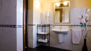 A bathroom with a white sink, a mirror with lights, a towel rack, and a vase with flowers. - Bed and Breakfast Charme (Sora)