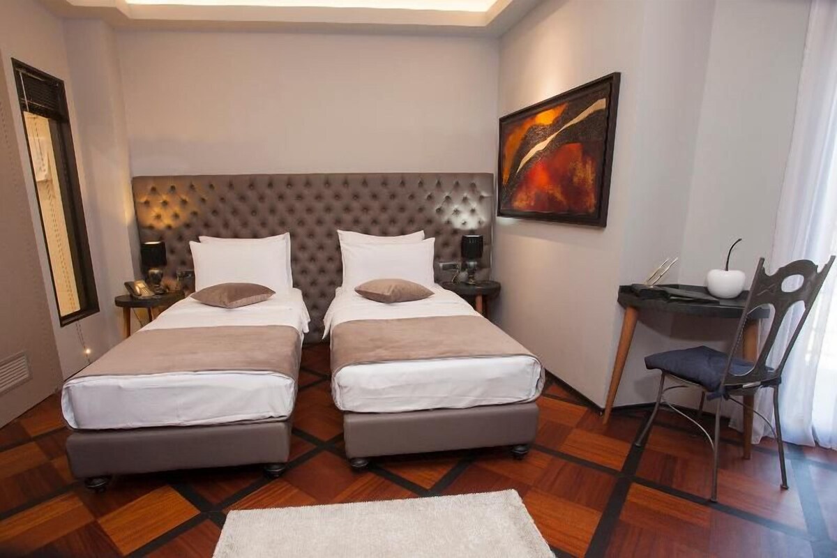 A hotel room with two beds, a desk, and a chair.