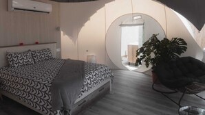 A bedroom with a bed, a potted plant, a round mirror, and a ceiling fan. - Fuente del Lobo Glamping  Bungalows - Adults Only (Pinos Genil)