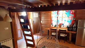 A cozy kitchen with a wooden interior, a dining table with chairs, a hanging chair, and a refrigerator. - Fuente del Lobo Glamping  Bungalows - Adults Only (Pinos Genil)