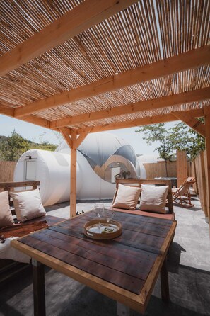 Une terrasse extérieure avec des meubles en bois et une table, entourée d’une pergola en bois.