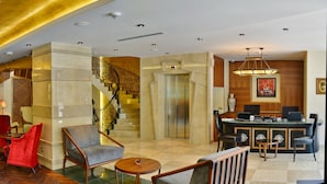 A spacious lobby with a grand staircase, comfortable seating areas, and a bar. - Warwick Ankara (Ankara)
