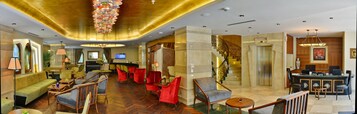 A spacious lobby with a grand staircase, comfortable seating areas, and a bar.