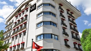 A multi-story hotel with balconies, a flag, and a sign indicating a hotel name. - Warwick Ankara (Ankara)