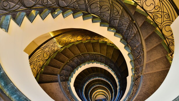 A spiral staircase with ornate metal railings and a mirrored wall. - Warwick Ankara (Ankara)